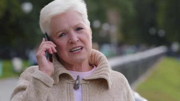 Blondýnka 60s drží telefon chatování s přítelem venku s příjemnou vzdálenou konverzaci s dospělými dětmi, starší generace a moderní technologie každodenní snadné použití koncept — Stock video