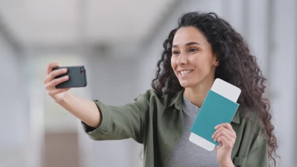 Portrait of girl blogger vlogger hispanic woman records video online call speaks into camera of mobile phone uses smartphone cellphone for broadcasting for blog vlog shows plane tickets and passport — Stock Video