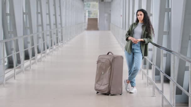 Ensam ledsen ung latinamerikansk kvinna kvinnlig passagerare turist står ensam på flygplatsen terminal järnvägsstation nära panoramafönster med resväska väntar på ankomst tåg plan innan du reser — Stockvideo