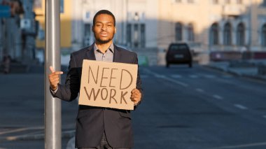 Karışık Yarış İşadamı İşaret parmağı Gerekiyor tabelası taşıyor. Açık havada duran genç adamın portresi. Milenyum erkek işçi kovulmuş. Salgın sırasında iş arıyorlarmış.