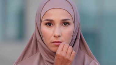 Müslüman, ciddi bir kadın, açık havada, tesettürlü, islamcı bir kızla karşı karşıya. Ağzını kapalı tutuyor. Ağzını kapalı tutuyor. Arap kadın sessiz tabela yapıyor, ırkçılık kavramı.