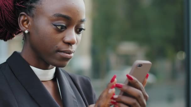 Chica afroamericana joven afro mujer de negocios usuaria femenina de pie en la ciudad escribiendo en el chat telefónico en la aplicación móvil de red utilizando el teléfono inteligente mensaje de redes sociales lee noticias internet wifi — Vídeos de Stock