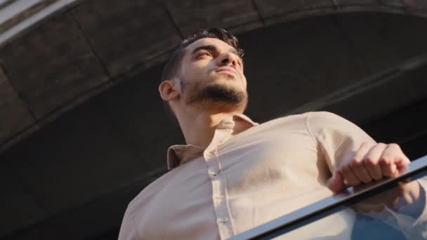 Spodní pohled mužský portrét zblízka hispánský obchodník stojící u zábradlí mrakodrapu kancelářské budovy balkón rozhlížející se po městě ulice městská krajina myšlení přemýšlející čeká. Latinský chlap na terase — Stock video