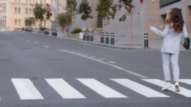 Güzel, aktif, dans eden, neşeli, beyaz, şık, siyah çantalı, beyaz bir kadın yaya geçidinde yürüyor, yaya geçidinde yürüyor, yaya geçidinde dans ediyor, yaya geçidinde yürüyor, yaya geçidinde yürüyor.