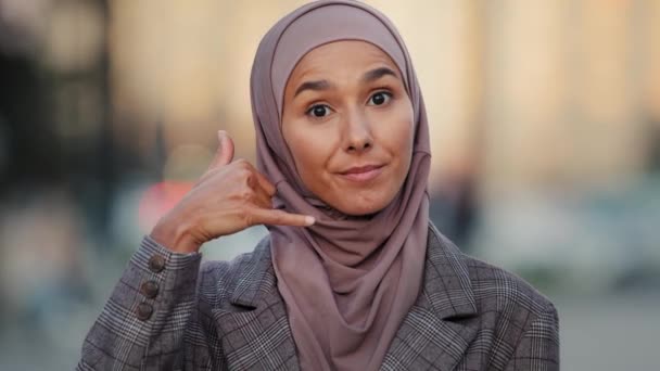 Llámame. Señal de llamada. Retrato atractivo islámico musulmán árabe mujer de negocios mirando a la cámara juguetona chica coqueteando en la ciudad sosteniendo teléfono mano teléfono gesto cerca de la oreja pidiendo oferta de contacto — Vídeos de Stock