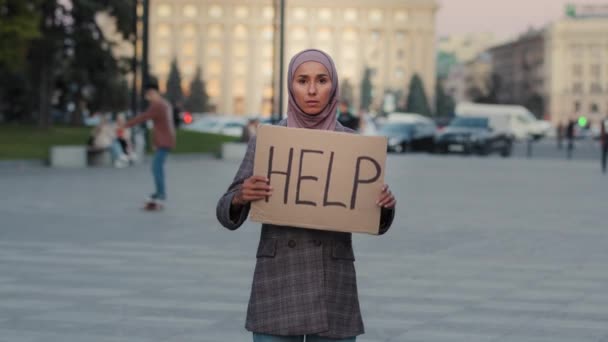 Мусульманин расстроен тем, что обеспокоенная женщина, носящая хиджаб, испуганная бедная девочка, стоящая в городе на улице с картонным плакатом, нуждается в поддержке. Протест женского активизма. Концепция расизма — стоковое видео