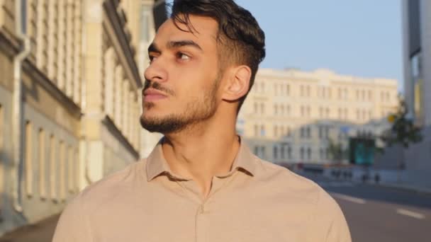 Porträt ruhigen hispanischen arabischen Geschäftsmann zu Fuß in der Stadt Gebäude Hintergrund. Nahaufnahme selbstbewusste junge erfolgreiche Mann bärtigen Touristentyp geht auf der Straße. Mann schaut sich um und geht ins Freie — Stockvideo