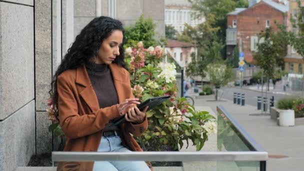 Serious focused busy pensive business woman with digital tablet girl with modern wireless gadget device chat browsing network distant works checking mail sitting on terrace balcony in office outside — Stock Video