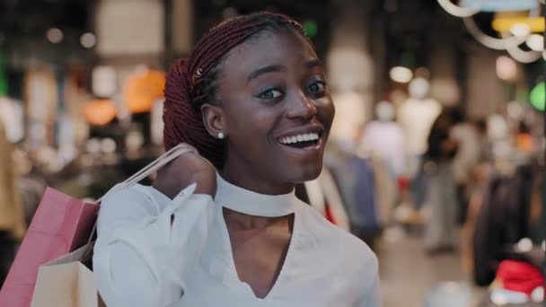 Чорна п'ятниця. Посмішка продавця щаслива афро-американська жінка збуджена дівчина стоїть в магазині з покупками сумок в торговому центрі купують одяг з великими знижками, продаючи портрет низьких цін. — стокове відео