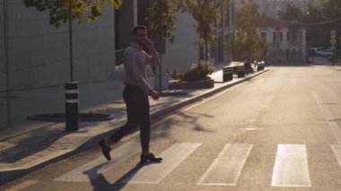 Yetişkin stili başarılı bir iş adamı resmi giysiler içinde cep telefonuyla konuşuyor iş arkadaşlarıyla telefon görüşmeleri yapıyor yaya geçidinde yürüyor, şehir yolunda yürüyor.