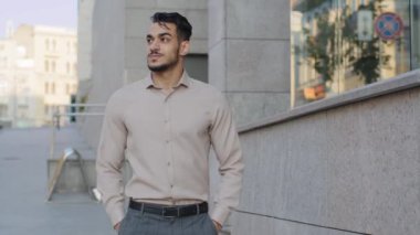 Başarılı stil sahibi, çekici, resmi kıyafetler giyen, tasasız, profesyonel iş adamı modern yaratıcı ofis şirketinin yakınlarında yürüyor ve sokak erkeğinin yürüyüşünden keyif alıyor.