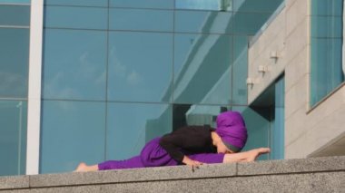 Müslüman, genç, tesettürlü, Müslüman, tesettürlü, Arap, Hintli, kadın, yogi, sokakta sicim üzerinde oturuyor, esnek spor yoga eğitimi veriyor, şehir esnekliği egzersizlerinde esneme hareketleri yapıyor.