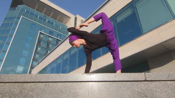 Muszlim iszlám lány jógi sport sportoló áll városi háttér épület csinál nyújtás edzés jóga tartja lábát a levegőben tartja láb magas kéz egyensúly ázsiai póz koncentráció koncepció — Stock videók