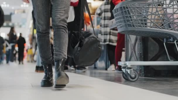 Primer plano piernas femeninas en zapatos oscuros mujer irreconocible niña terrorista deja bolsa negra con bomba en el centro comercial supermercado piso tienda en el lugar público. Peligro tictac detonador temporizador en el mercado — Vídeos de Stock