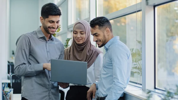 Colegas multiétnicos ouve líder de equipe árabe explicar aplicação tarefa corporativa para diversos trabalhadores empresários indianos olhando na tela do laptop trabalhando juntos, conceito brainstorm trabalho em equipe — Fotografia de Stock