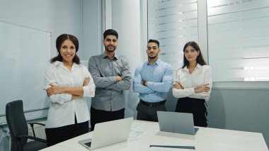 Kollarını kavuşturup gülümseyen neşeli, çok kültürlü grup takım ruhu, destek, güç gösteriyor. Şirket reklamı için çalışan iş arkadaşları. Liderlik kavramı, takım çalışması, birlik