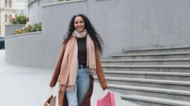 Dertsiz, esmer, genç, alışveriş meraklısı, alışveriş meraklısı, şık bir palto ile alışveriş meraklısı, alışverişin ardından parlak paketler, indirimli mutluluk, kara Cuma konsepti.