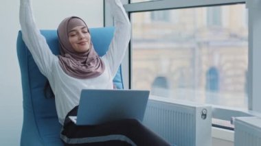Rahat, güzel, Arap iş kadını Müslüman bir kadın rahat koltuğunda oturur, meditasyon yapar, olumlu, sakin, Arap bir kadın rahatlar, ellerini başının arkasına koyar bilgisayar gerdirme rüyasından dinlenir, zihin huzuru hisseder.
