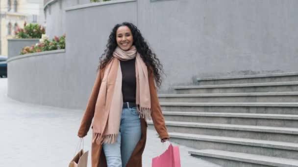 Gelukkig zorgeloos brunette meisje jonge vrouw shopper consument shopaholic in stijlvolle jas wandelen stad met heldere pakketten aankopen na het winkelen bewegende geluk met kortingen, zwarte vrijdag concept — Stockvideo