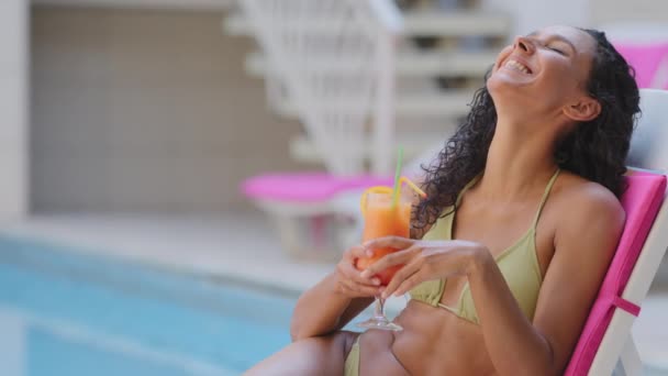 아주 날씬하고 섹시 한 여성 이 술 칵테일을 마시며 추파를 던지며 럭셔리 한 휴가를 즐기고 있습니다. 아름다운 햇볕에 그을리는 스페인 소녀가 스파 호텔에서 과일 주스를 마시는 수영장에서 일광욕을 즐기는 모습 — 비디오