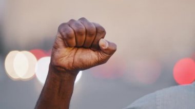 Yakından sıkılmış güçlü erkek yumruğu kaldırıldı. Siyahi Afrikalı Amerikalı yetişkin adam ayrımcılığa karşı el hareketleriyle ırkçılık ayrımcılığına karşı protesto gösterisi yapıyor