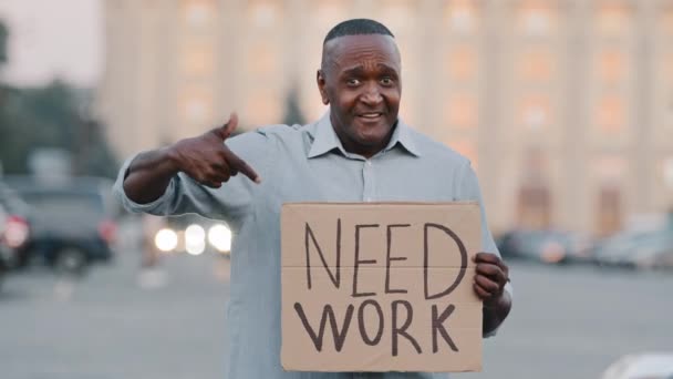 Empresário negro afro-americano infeliz segurando papelão Precisa de trabalho emocional apontando no sinal. Estressado frustrado homem segurar cartaz procurando trabalho durante pandemia fala sobre si mesmo ao ar livre — Vídeo de Stock