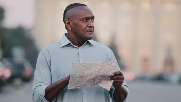 Adult mature black foreign tourist look for address lost african american man traveler in new city standing on street outdoors with map searching way road destination navigation route looking around — Stock Video