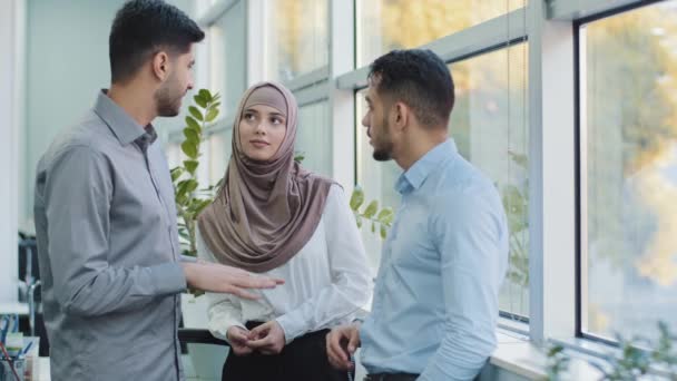 Multiethnic colleagues arab muslim woman in hijab and two Indian millennial male discuss corporate task. Diverse workers businesspeople working together in modern office, teamwork brainstorm concept — Stock Video