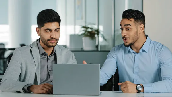 Indiano oriental millennial homens de negócios olhando para tela do laptop discutindo projeto, satisfeito com resultado de negociações colegas árabes trabalhando juntos no escritório moderno, recebendo boas notícias — Fotografia de Stock