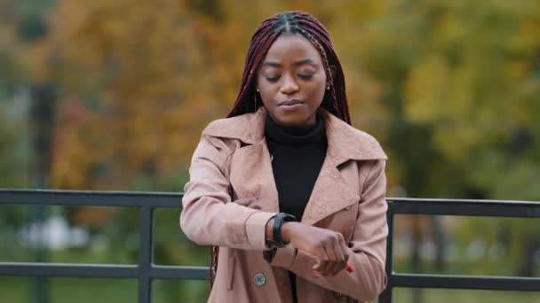 Se está quedando sin tiempo, date prisa, para llegar tarde concepto. Una joven aparece de guardia, contando minutos, corriendo. Retrato de hermosa chica afroamericana con peinado afro de pie en el parque de otoño solo — Vídeo de stock