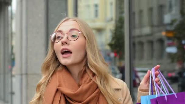 Close-up atractiva chica saludando mano en la calle invita a ir de compras, señalando a las bolsas de mujer mostrando pulgares hacia arriba caucásico señora agitar compras al aire libre comprador femenino disfrutar de descuentos en viernes negro — Vídeos de Stock