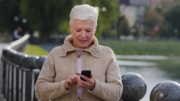 Eufórikus ősz hajú érett nő nézi a mobiltelefon képernyőn, olvasás sms váratlan kiváló értesítést, egyre nagy hír, érzés izgatott az online lottó győzelem élvezze a győzelem pillanatát — Stock videók