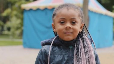 Çok ırklı çocuk yüzünü kapat. Sakin ol, küçük kız. Kamera portresine bak. Saçı örülü şirin bebek, dışarıda afro-amerikan çocuğu.