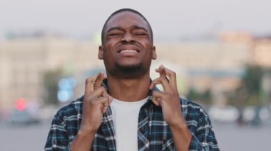 Afrika kökenli Amerikalı adam şehirde dua ederek dua ediyor. Dua, gelecekte zafer kazanmayı umuyor, umut ediyor. Umut dolu Afro adam açık havada iyi şanslar diliyor.