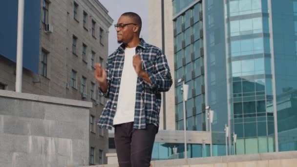 Stijlvol vrolijk vrolijk Afrikaans man Afrikaans man zingen lied zingt doen alsof gitaar spelen drums muzikant genieten van muziek dansen buiten stad gebouw stedelijke achtergrond dans plezier hebben op straat — Stockvideo