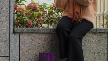 Güzel bir kız alışveriş poşetleriyle şehir caddesinde oturuyor. İnternetten alışveriş yapan kadın. Milenyum genç bayanının cep telefonuyla iletişim kurduğunu doğrulayıcı şekilde başını salla.