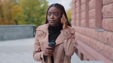 Düşünceli Afro-Amerikan kadın kahve içiyor uzaktan bakıyor. Düşünceli siyah kadın, cep telefonuyla konuşuyor. Problemleri çözmeyi düşünüyor, karar veriyor.