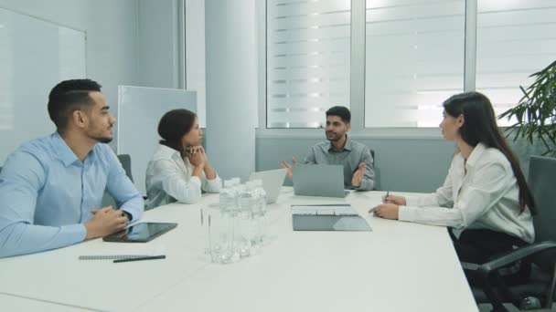 Empresario indio hablando con compañeros de negocios o socios sentados en la mesa de conferencias, líder masculino discutiendo trabajo en reunión de equipo o negociaciones de grupo teniendo conversación con clientes — Vídeos de Stock