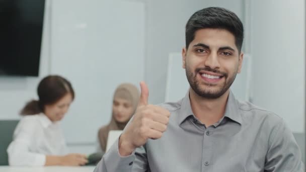 カメラでジェスチャーのように親指を立てる幸せな笑顔のアラブ男性ビジネスリーダーの肖像画。従業員は仕事に満足し、素晴らしいチームで働いています。会社のサービスに肯定的なフィードバックを与えるクライアント — ストック動画