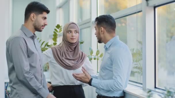 Sokszínű barátok többnemzetiségű kollégák arab muzulmán nő hidzsábban és két indiai férfi csevegnek, barátságos emberek élvezik a kellemes beszélgetést szünetben, férfi mesél történet érzés boldog és elégedett — Stock videók