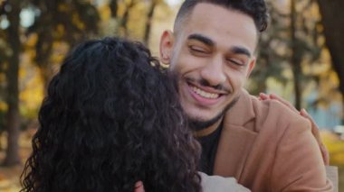 Portre, neşeli İspanyol genç adam, sonbahar parkında uzun zamandır mutlu İspanyol çiftle tanışmayı bekleyen, tanınmayan esmer kadına sıkıca sarılıyor. Yakından bakınca yakışıklı sakallı adam gülümsüyor.