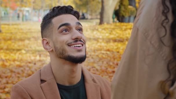 Közelkép portré spanyol fiatal srác térdel előtt barátnője szabadban férfi, hogy házassági ajánlatot gyönyörű barna nő vonzó hölgy vissza kilátás boldog pár szorosan ölelés őszi parkban — Stock videók
