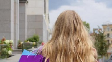 Alışveriş paketleriyle gezen mutlu bir kız, beyaz bir kadınla sokakta yürüyor. Elinde çantalar, dışarıda alışveriş yapan bir kadın kameraya bakıp gülümsüyor. Alışveriş düşkünü genç bayan, indirimli satış indirimli cuma gününü kutluyor.