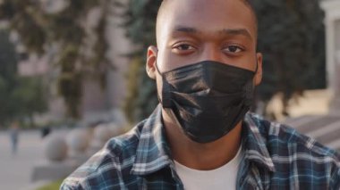 Yakın plan erkek portresi Afro-Amerikan erkek hasta adam şehir sokaklarında karantina covid 19 Coronavirus salgın hastalığını önleme konsepti kamerasına bakıyor.
