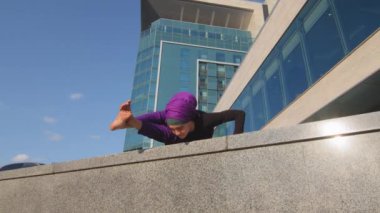 Alt görüşe göre Müslüman İslami güçlü güçlü atletik kadın tesettüre girmiş güçlü kız el ele tutuşarak denge kuruyor kadın yoga antrenmanında şehirde sokak inşaatı üzerine spor yapıyor.