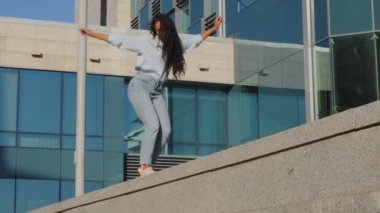 Aktif, neşeli, neşeli, genç kız model kazanan şehir terasında yürüyor arka planda dans ediyor, dans ediyor fener döndürüyor, hafta sonunun tadını çıkarıyor, gülüyor.