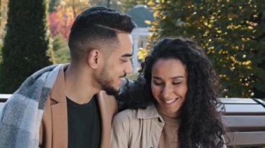 Sonbahar parkında battaniyeyle örtülü mutlu Arap çift. Güzel kadın kahve içiyor ve ekoseli erkeği dikkatlice kucaklıyor. Sevgili kız ve erkek sevgili sevgililer randevularında iletişim kuruyor.