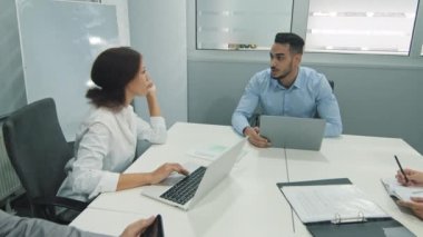 Motive olmuş Arap takım lideri iş adamı şirket geliştirme stratejisini genç meslektaşlarına anlatıyor. Başarılı çok ırklı iş adamları ofiste birlikte çalışmaktan keyif alıyorlar.