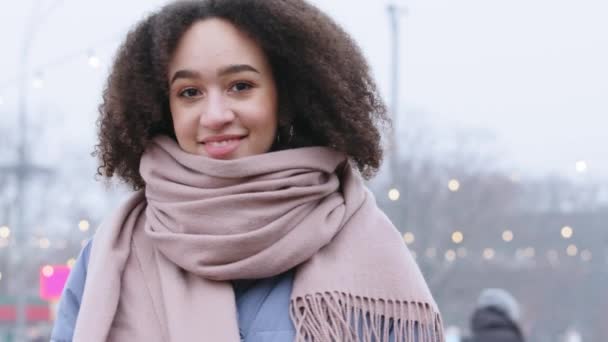 Portret uśmiechniętych młodych kręconych włosów mieszane rasy afrykańskiej amerykańskiej dziewczyny kobieta ze stylową fryzurą afro nosi szalik na zewnątrz w zimną pogodę pozowanie patrząc na uśmiech aparatu stojącego na ulicy miasta — Wideo stockowe