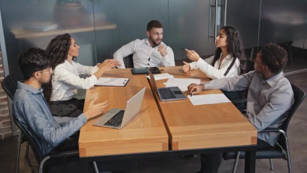 Colegas felizes bem sucedidos discutindo ativamente projeto ideia equipe de negócios multirracial sorrindo sentado no escritório brainstorm jovens gerentes na sala de conferências disputando funcionários com laptops trabalho em equipe — Vídeo de Stock